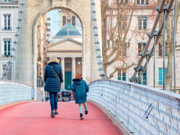 deux lyonnaises traversent en trotinette la passerrelle du college a lyon