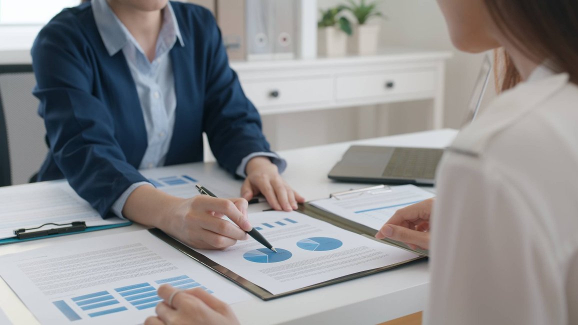 Réunion de professionnelles examinant des documents et discutant de graphiques en secteurs.