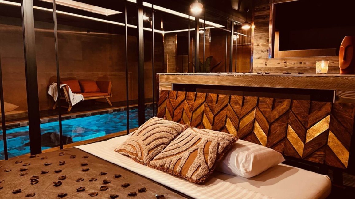 love room mojo pool de belleville sur saone avec decoration africaine et vue sur piscine interieure depuis le lit