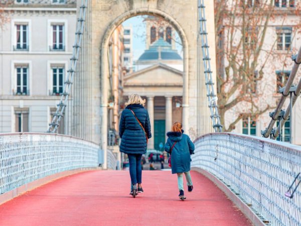 deux lyonnaises traversent en trotinette la passerrelle du college a lyon